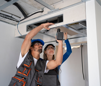 Two people working on ac system inside home